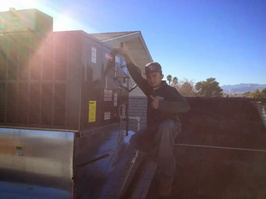 HVAC technician performing AC Tune-Up on a rooftop unit in Holly